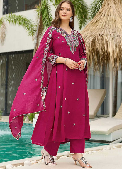 Woman in a pink traditional outfit with embroidery standing by a poolside.