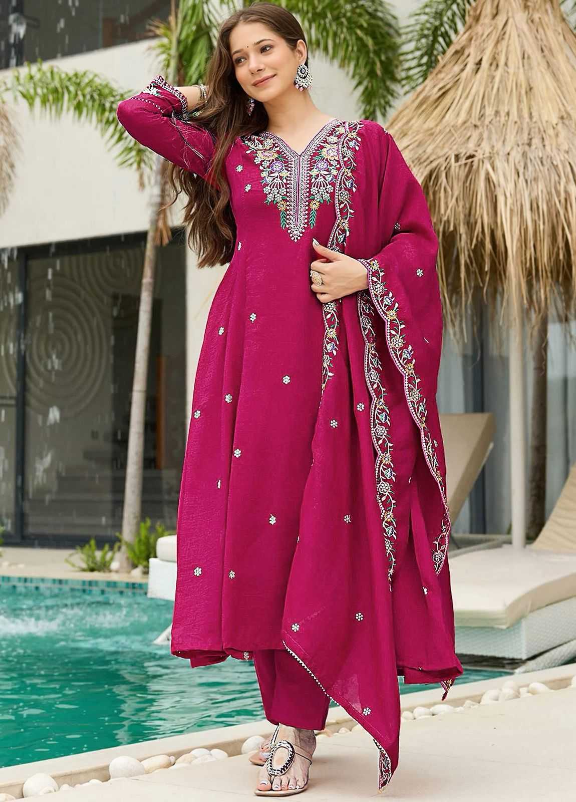 Woman in a pink traditional outfit with silver embroidery by a poolside.