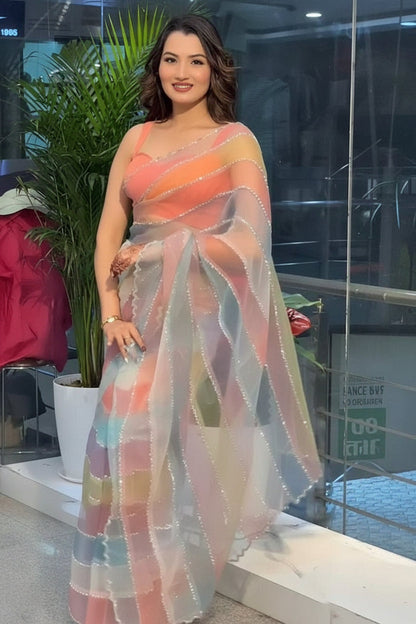 Woman wearing a colorful saree in an indoor setting with plants and furniture.