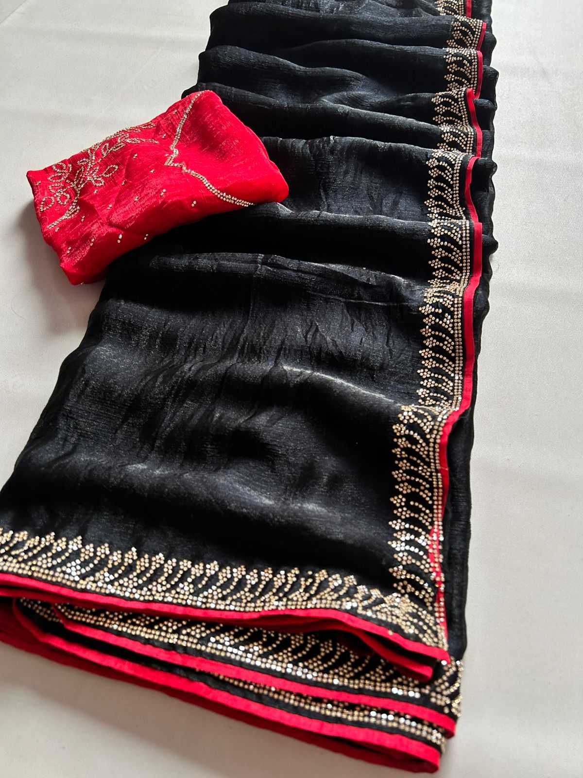 Black saree with gold and red border on a white background
