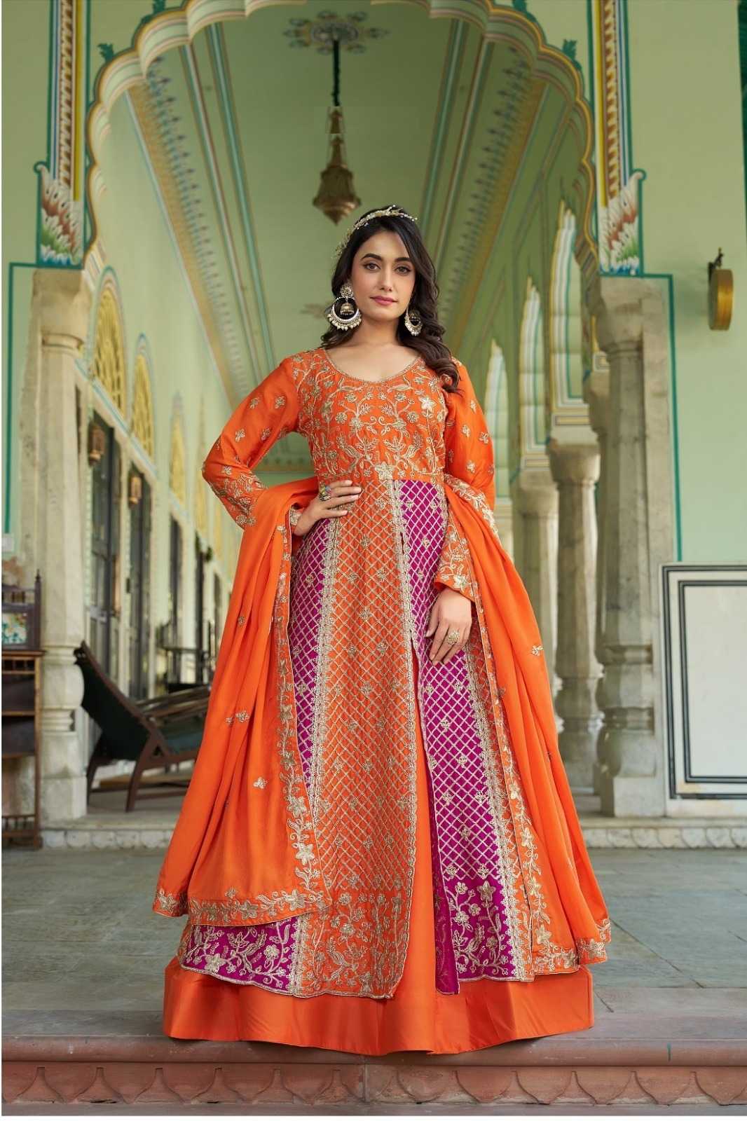 Woman in an orange and purple traditional outfit standing in a decorative architectural setting.