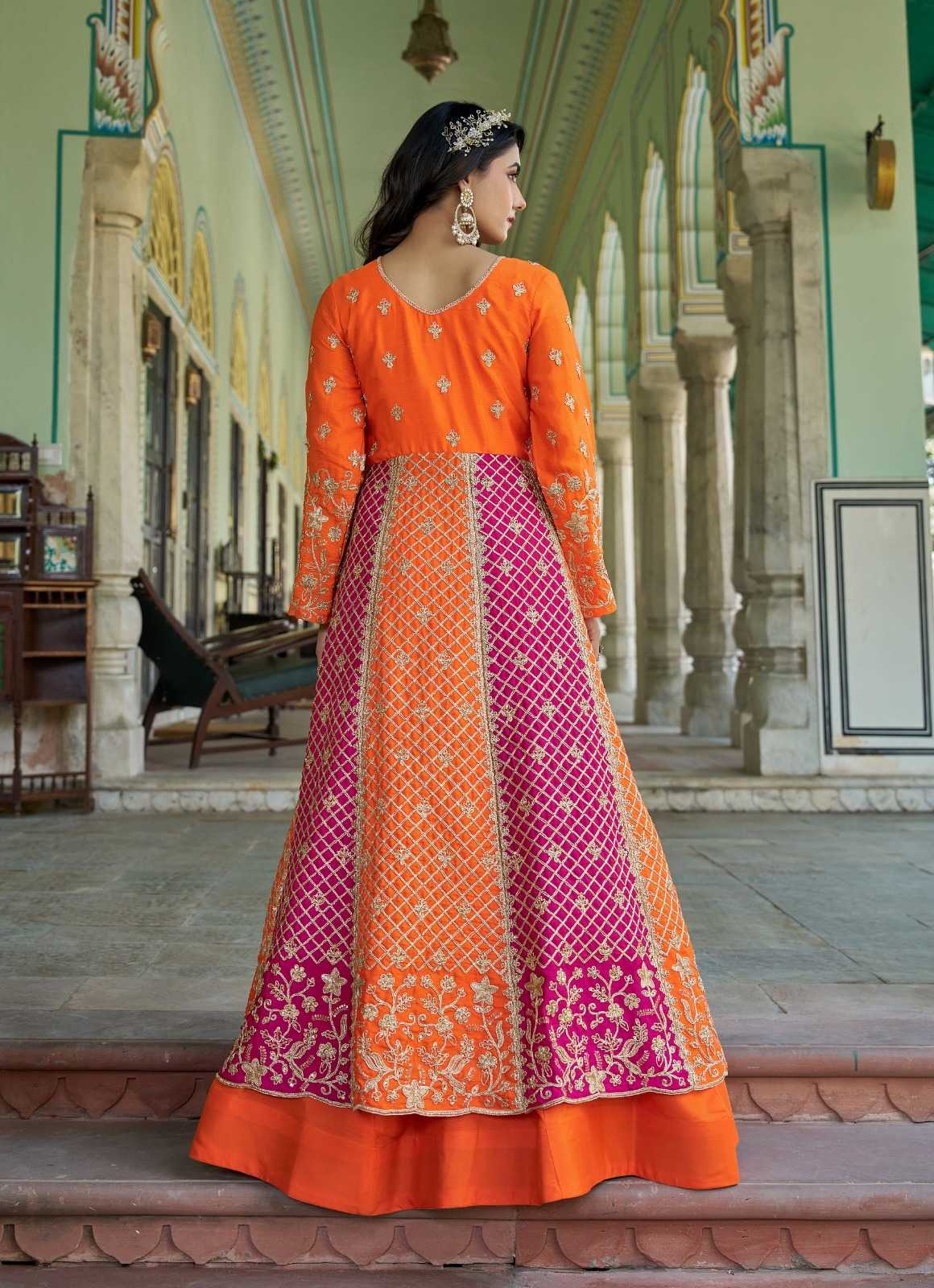 Woman wearing an orange and pink traditional outfit in a decorative interior setting