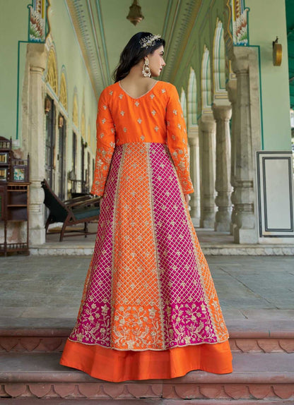 Woman wearing an orange and pink traditional outfit in a decorative interior setting