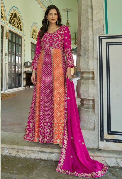 Woman in a pink and orange traditional outfit standing in an ornate indoor setting.