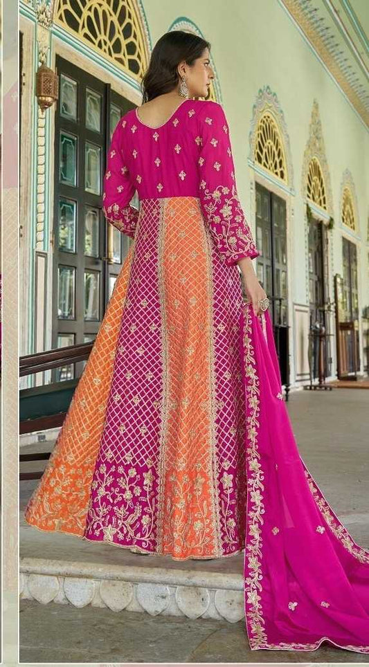 Woman in a pink and orange traditional outfit standing in front of an ornate building.
