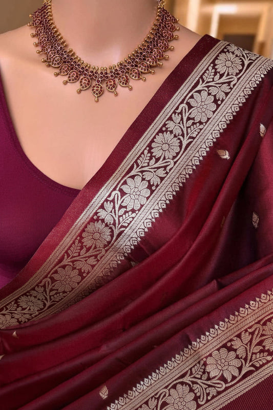 Maroon saree with gold embroidery and a matching necklace on a mannequin.