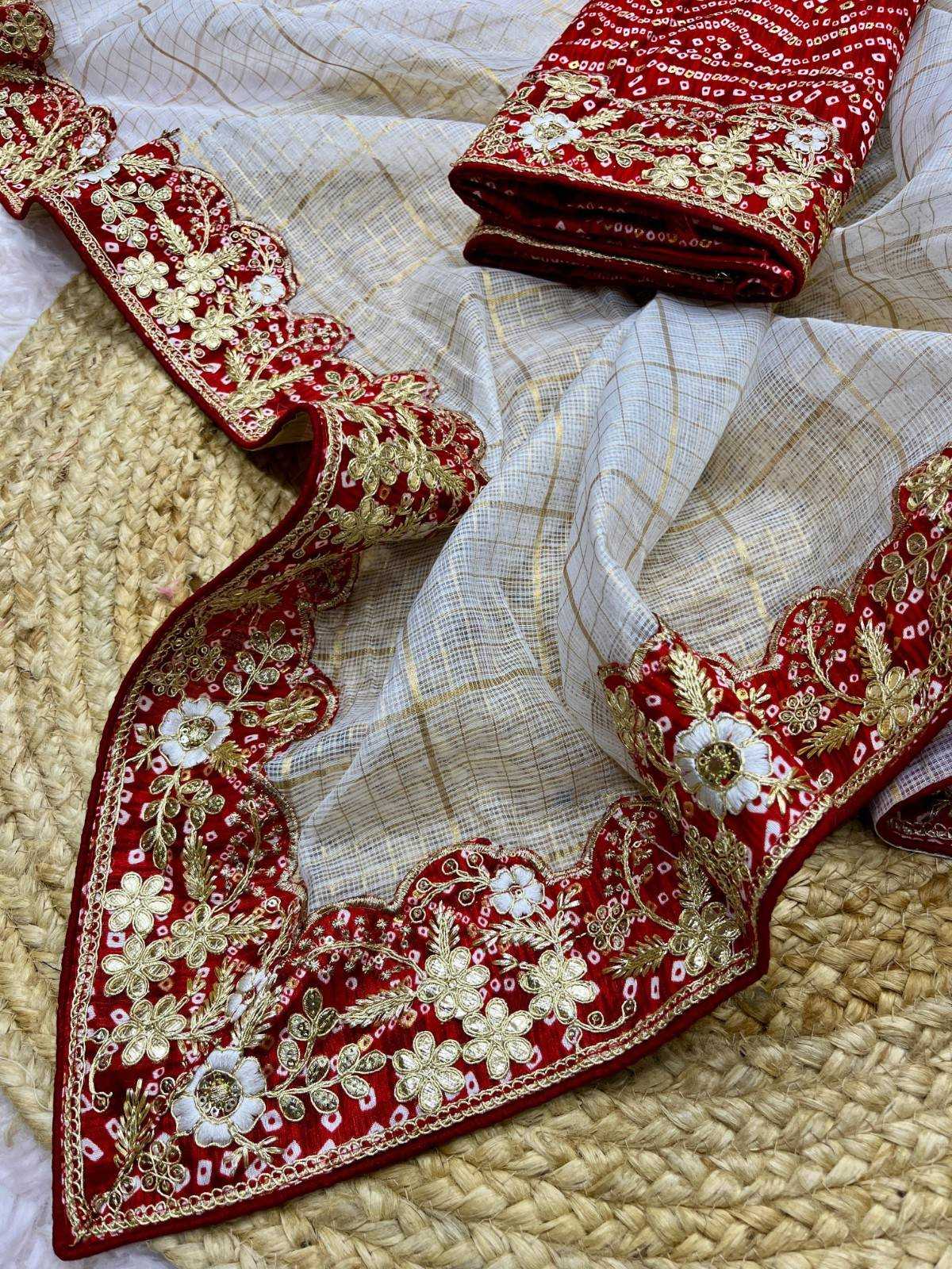 Red and white embroidered ethnic fabric set with a sheer white dupatta featuring gold zari borders and red sections heavily embellished with white and gold floral embroidery, laid out on a woven straw mat.
