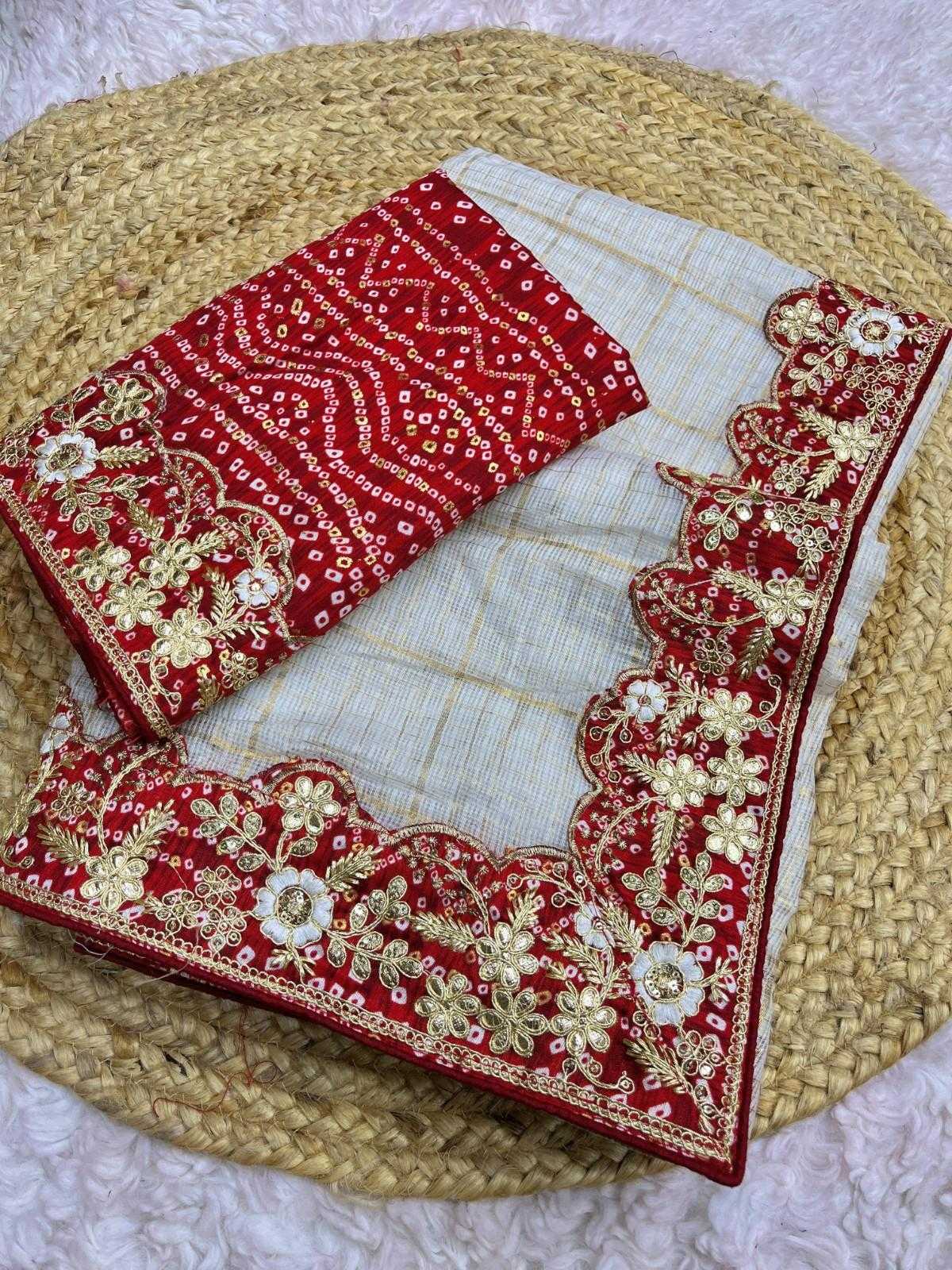 A folded red and off-white fabric set with intricate gold floral embroidery and scalloped borders, displayed on a woven straw mat over a white textured surface.