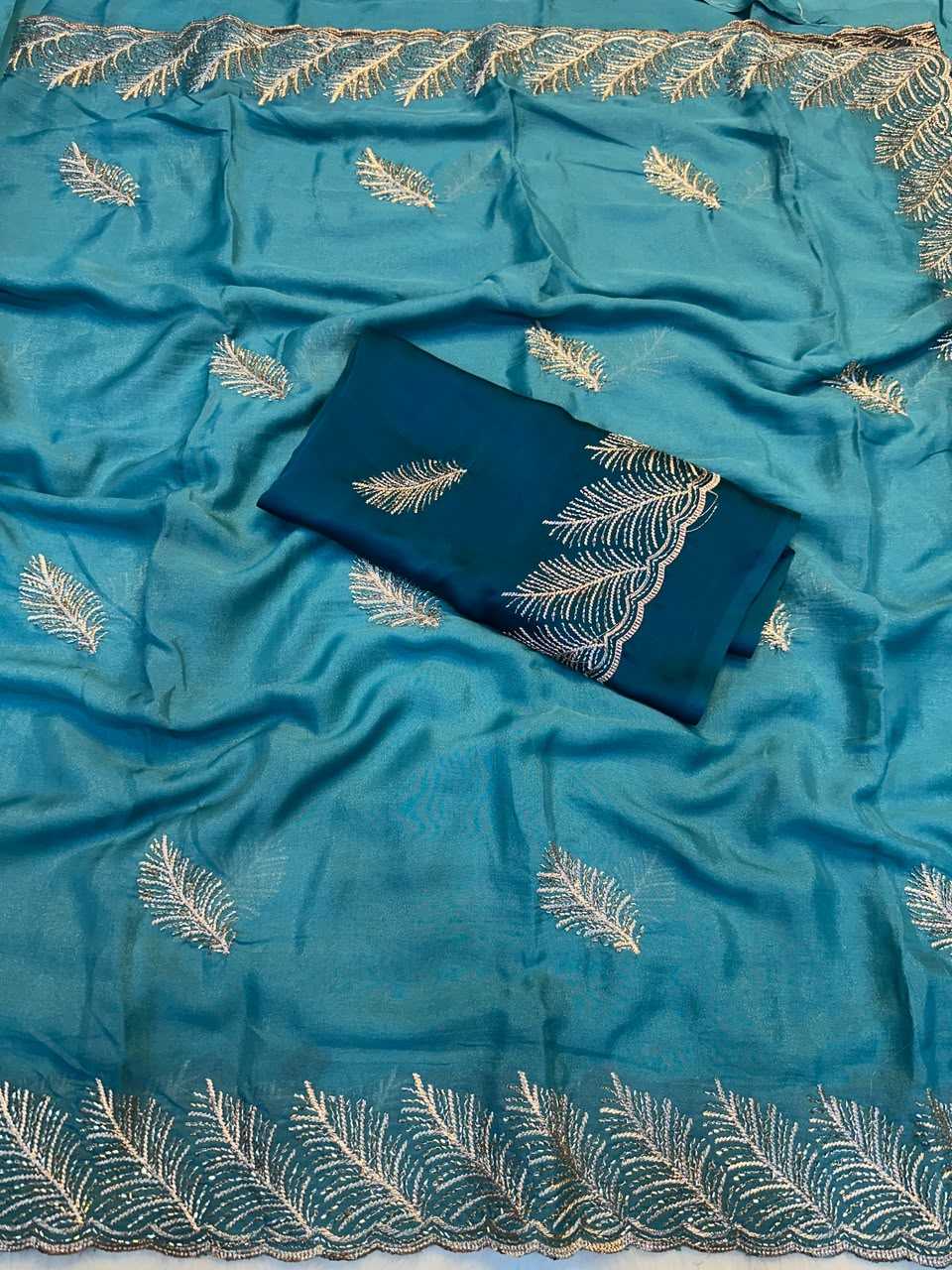 A teal blue fabric garment or textile set with embroidered leaf motifs and a matching folded fabric piece placed on top, photographed against no visible real environment.