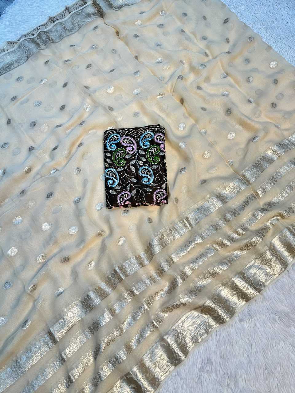 A beige sheer dupatta with metallic gold zari borders, scattered gold and silver mirror work dots, and a small black embroidered patch featuring colorful paisley motifs.