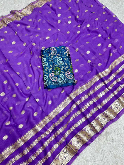 Purple silk saree with scattered metallic gold dots, a wide striped border with gold zari work, and a folded blue embroidered fabric piece placed on top.
