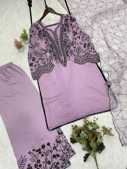 Lavender outfit with black floral embroidery on a textured surface with flowers.