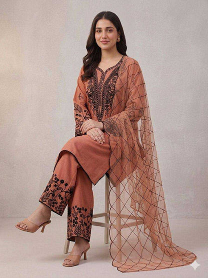Woman wearing a peach-colored traditional outfit with black embroidery against a plain background