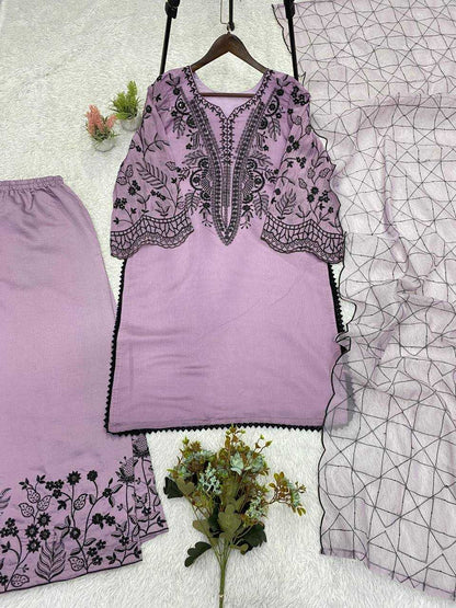 Purple embroidered top and pants set on a textured surface with floral decorations.