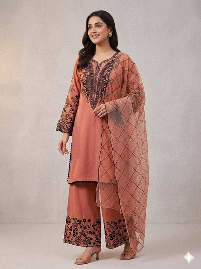 Woman wearing a peach-colored traditional outfit with intricate patterns on a plain background
