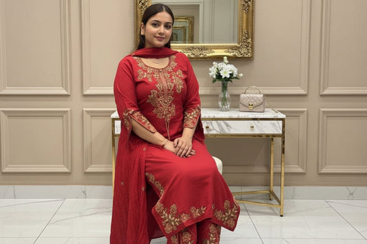 Person wearing a red embroidered traditional outfit in a decorated room.