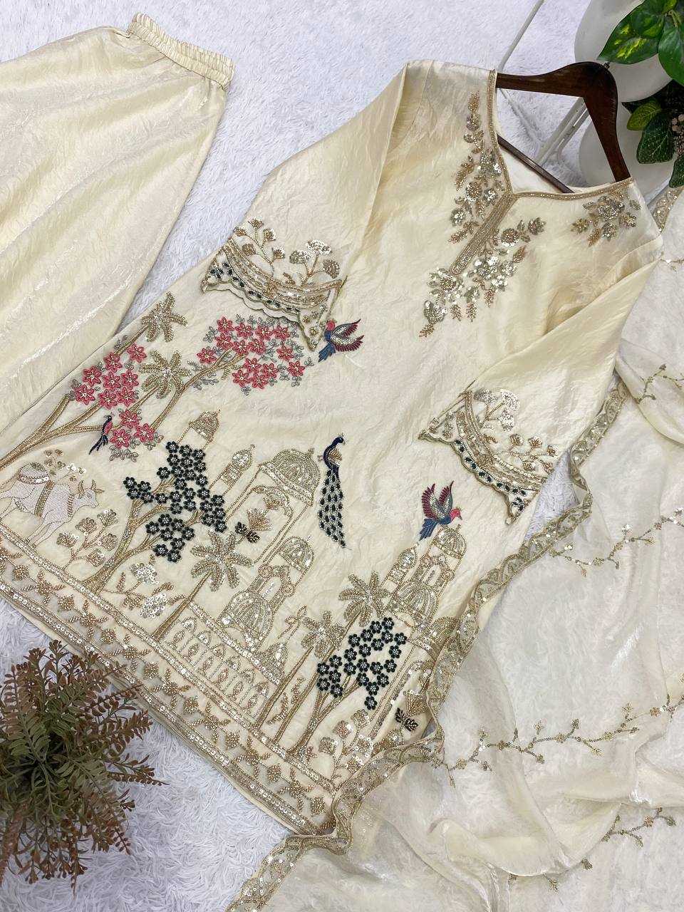 Embroidered cream-colored garment with floral and landscape designs on a light background.