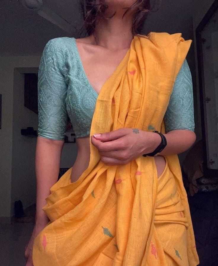 Person wearing a teal blouse and yellow saree in an indoor setting