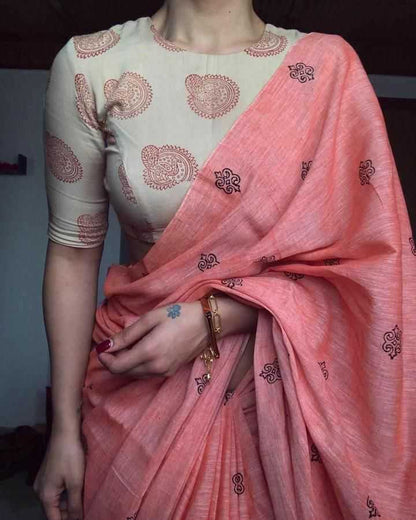 Person wearing a white blouse with red patterns and a pink saree with black designs.
