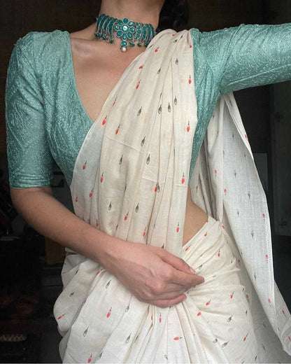 Person wearing a light blue blouse with a white saree featuring small patterns.