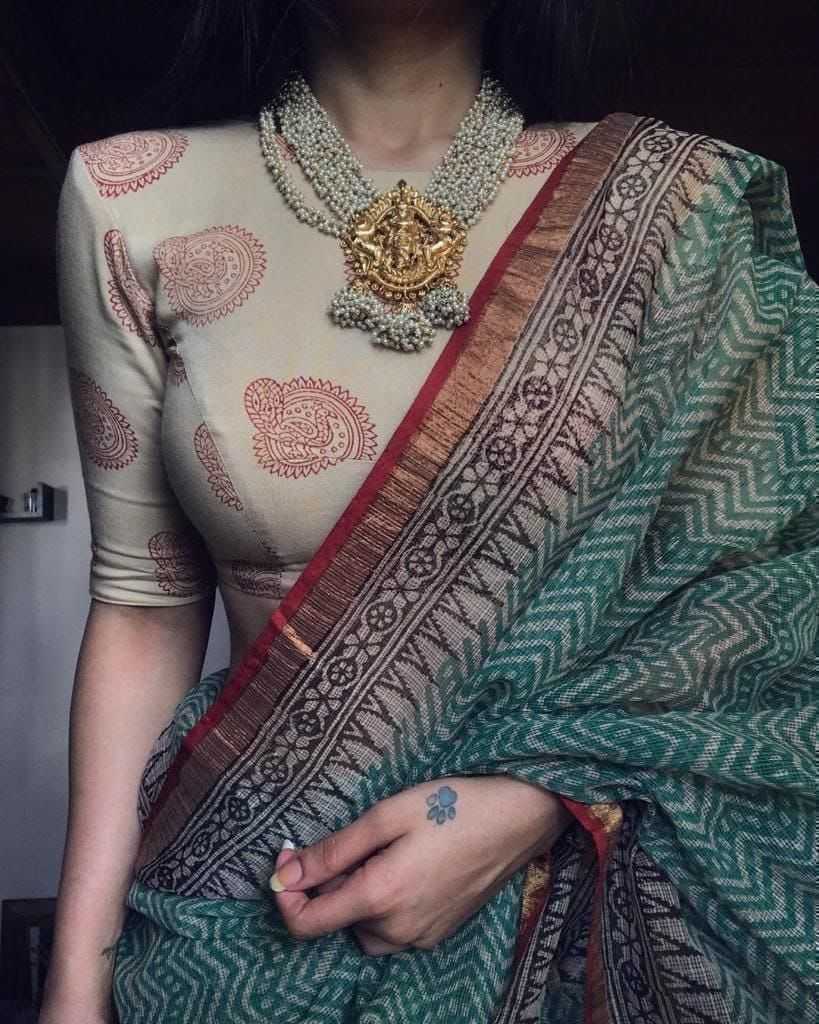 Person wearing a traditional saree with intricate patterns and jewelry.