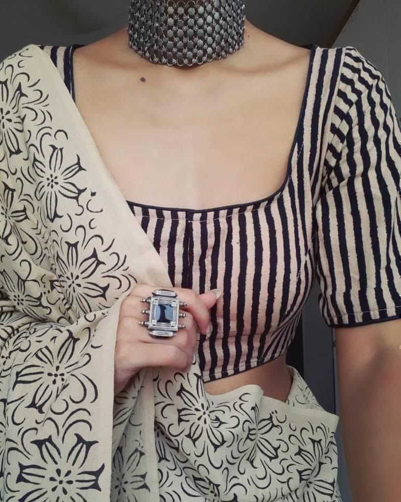 Person wearing a black and white striped blouse with a patterned scarf and jewelry.
