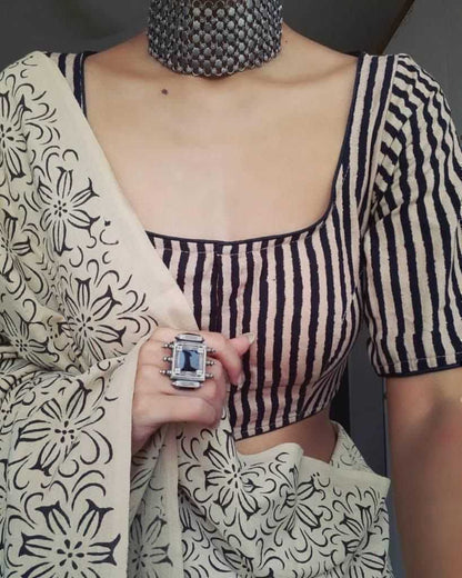 Person wearing a black and white striped blouse with a patterned scarf and jewelry.