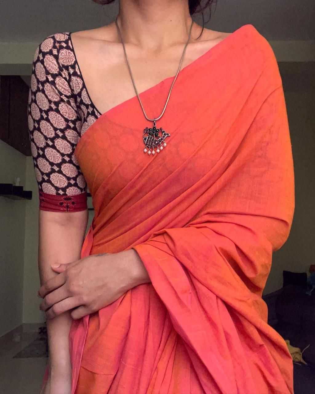 Person wearing an orange saree with a black blouse, holding a child.