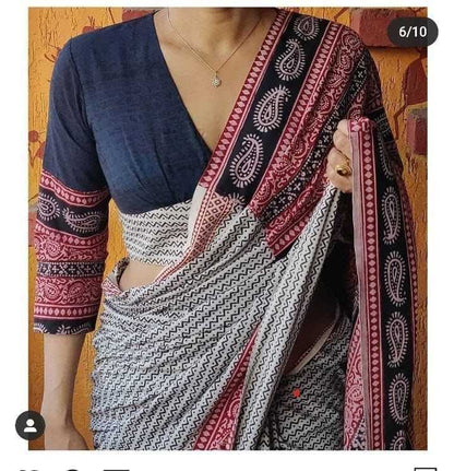 Saree with a blue blouse and patterned border against a wooden background