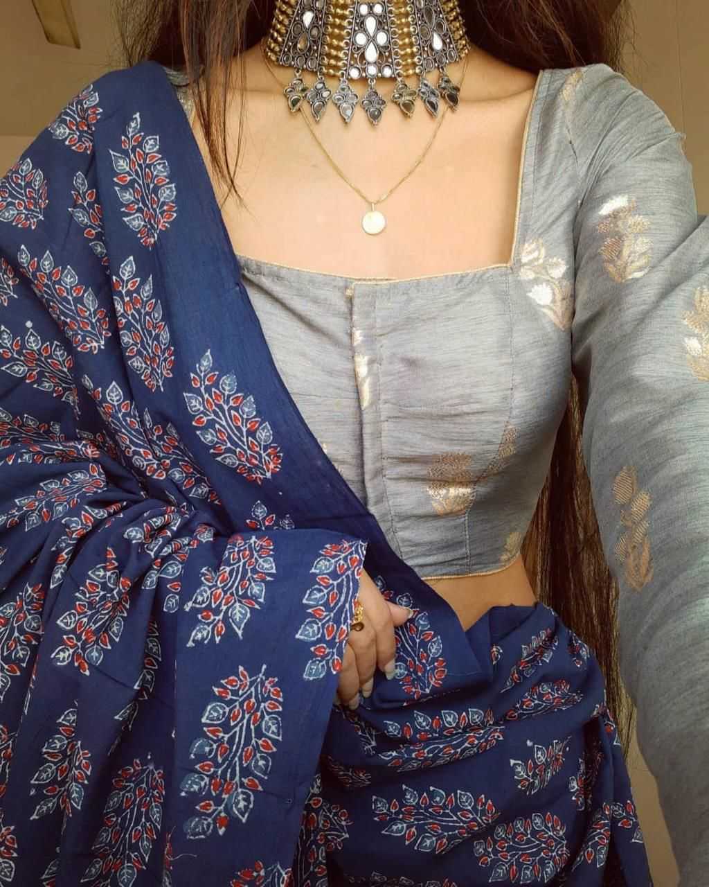 Person wearing a blue floral saree with a gray blouse, holding the saree.