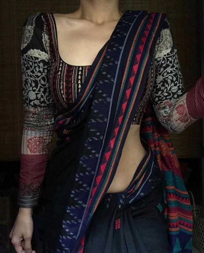 Person wearing a colorful patterned saree with a dark background