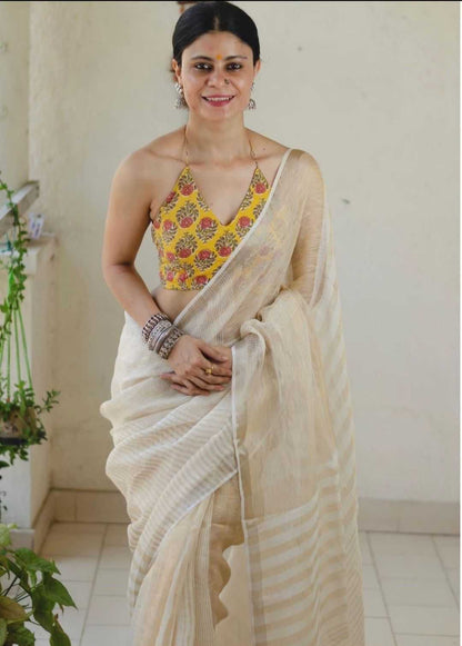 Woman wearing a floral top and beige saree indoors.