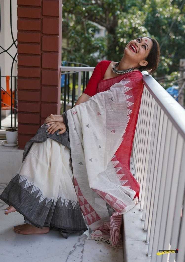 Woman in a red and white saree standing on a balcony