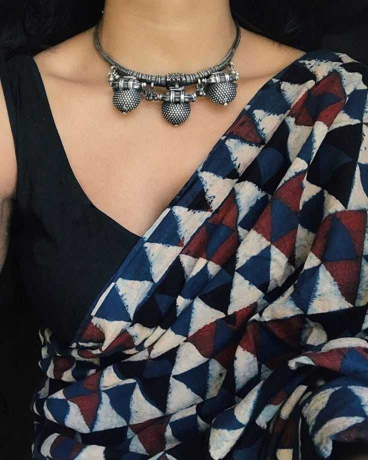 Person wearing a geometric-patterned saree with a necklace