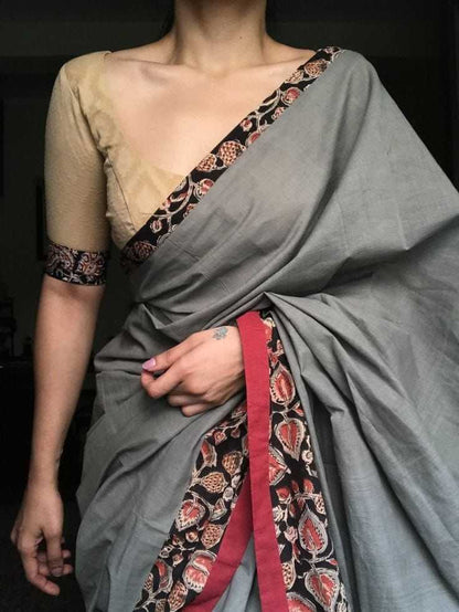 Person wearing a traditional saree with intricate patterns on a dark background