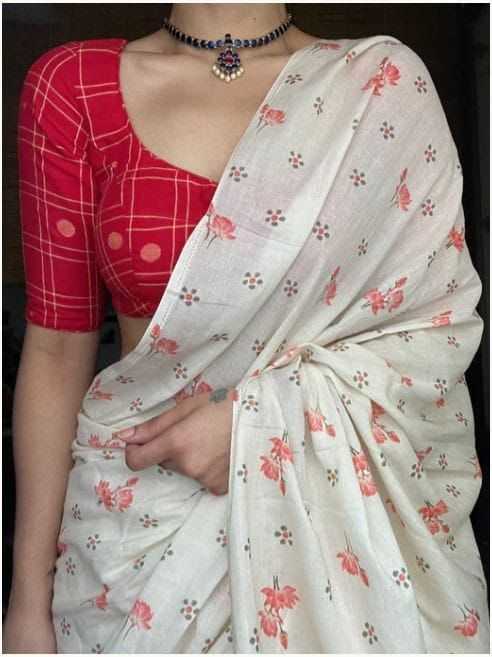 Person wearing a red blouse with a white floral saree against a dark background