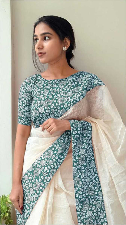 Woman wearing a green and white saree with a floral pattern against a plain background
