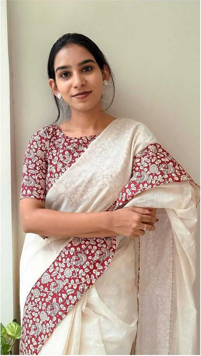 Woman wearing a white saree with red and white floral patterns.