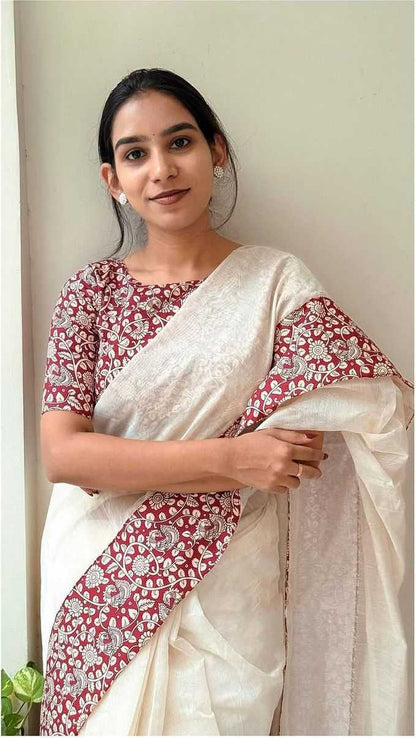 Woman wearing a white saree with red and white floral patterns.