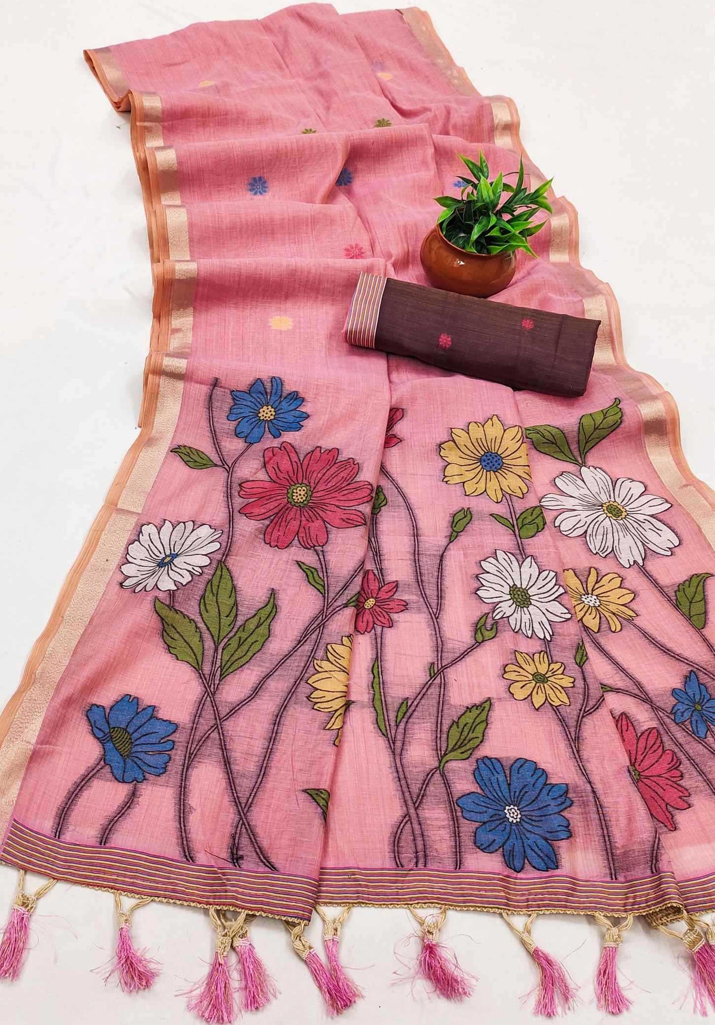 Pink saree with floral embroidery and tassels on a white background