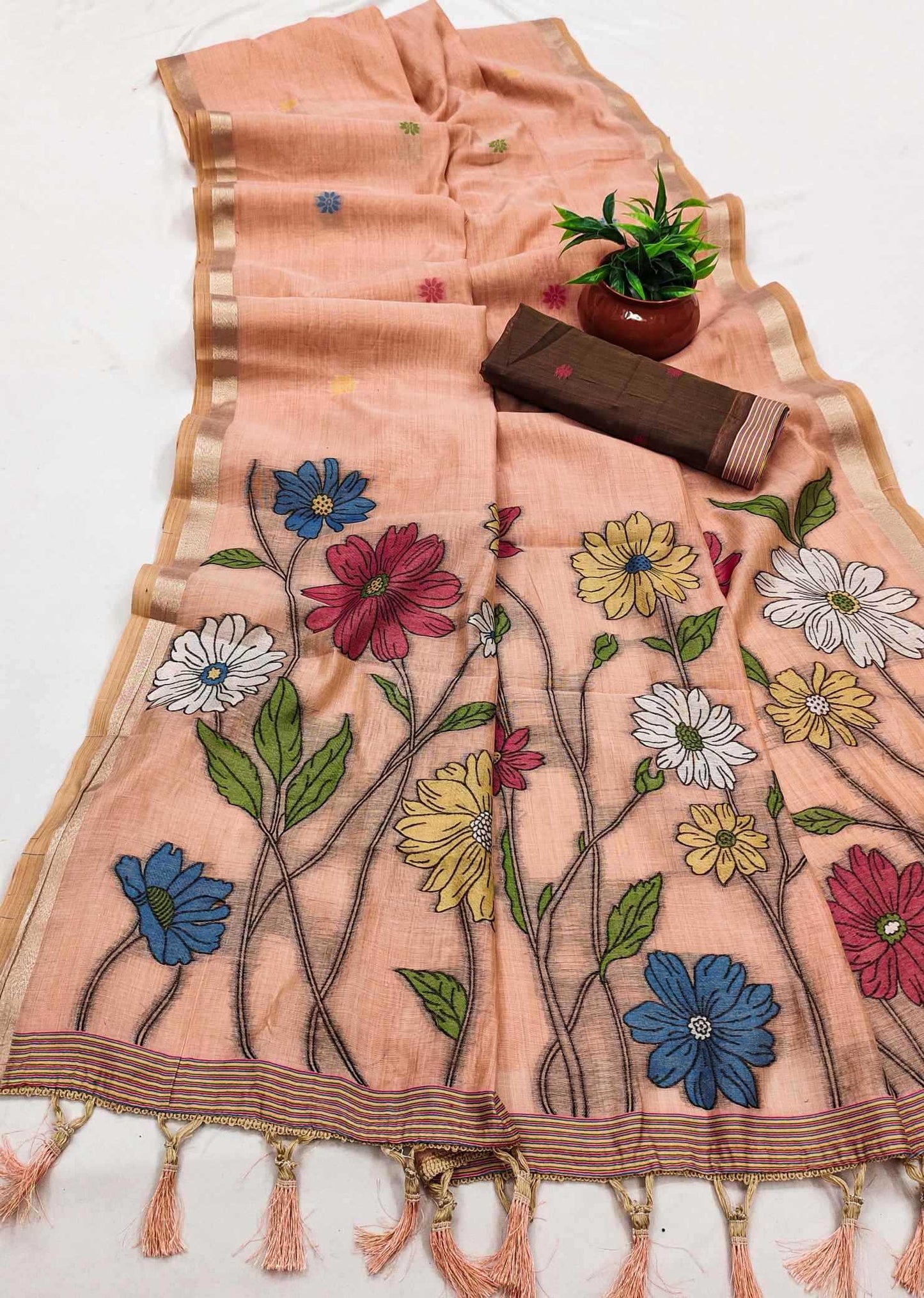 Embroidered floral design on a peach fabric with tassels, placed on a white surface.