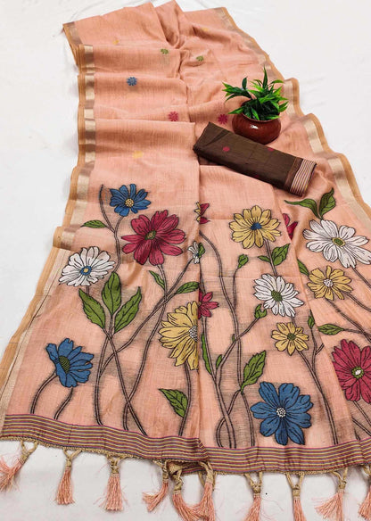 Embroidered floral design on a peach fabric with tassels, placed on a white surface.