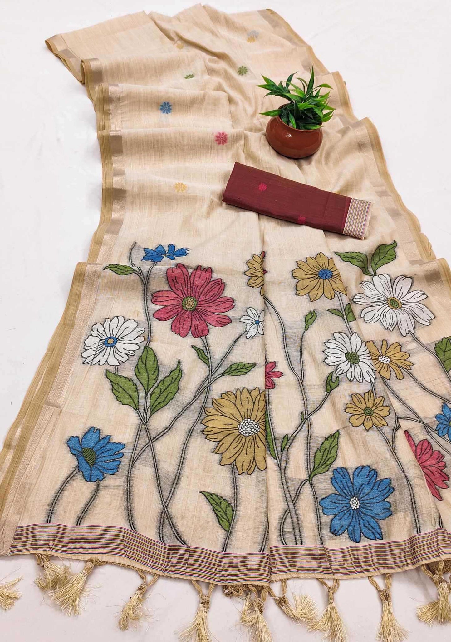 Beige scarf with floral embroidery and a small plant on a white background