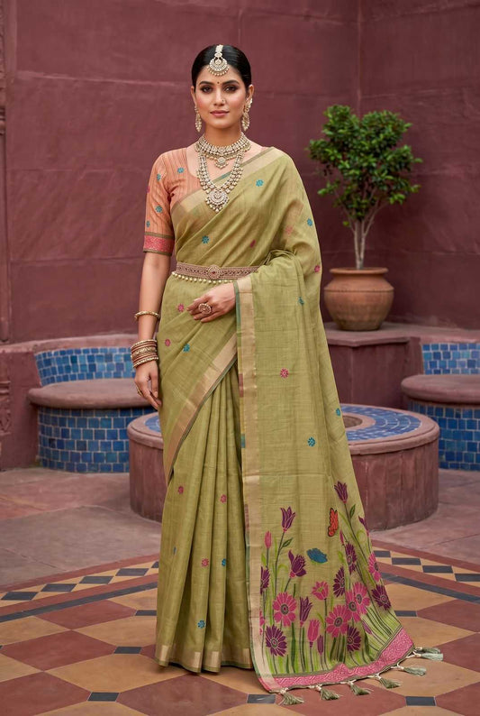 Woman in a traditional green saree with floral patterns standing in an outdoor setting.