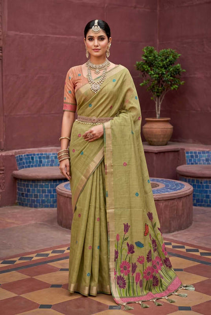 Woman in a traditional green saree with floral patterns standing in an outdoor setting.