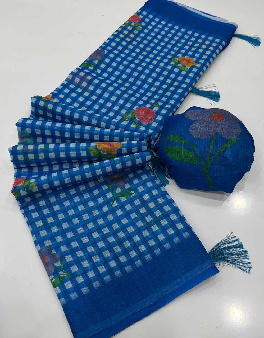 A blue checkered dupatta with floral embroidery and tassel ends, shown alongside its matching blue embroidered pouch on a white surface.