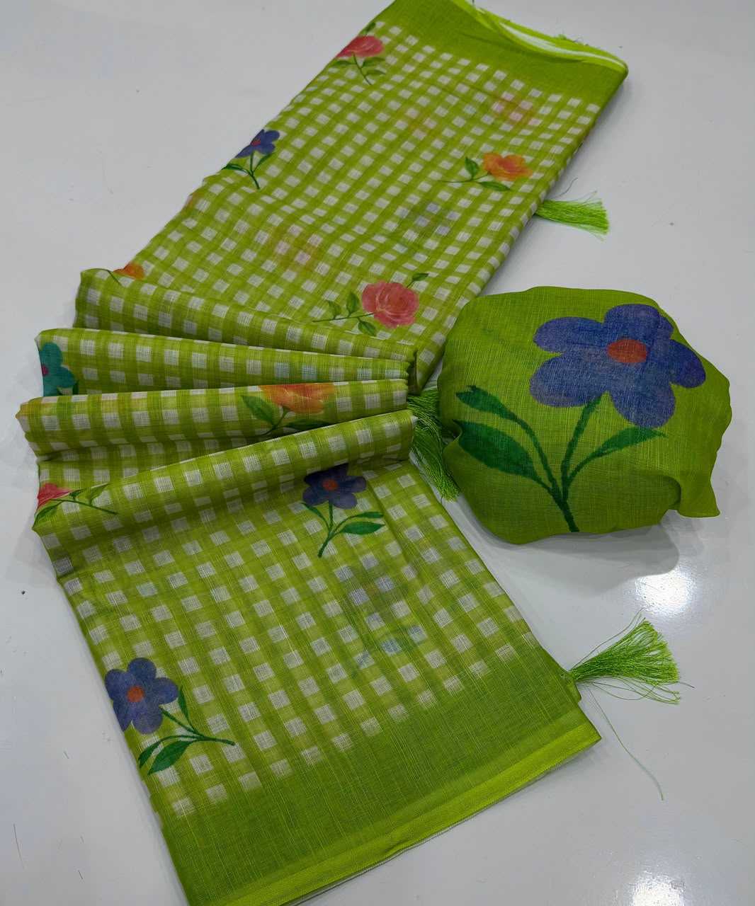 A lime green and white gingham check saree with colorful floral prints, displayed alongside its matching green fabric pouch on a white surface.