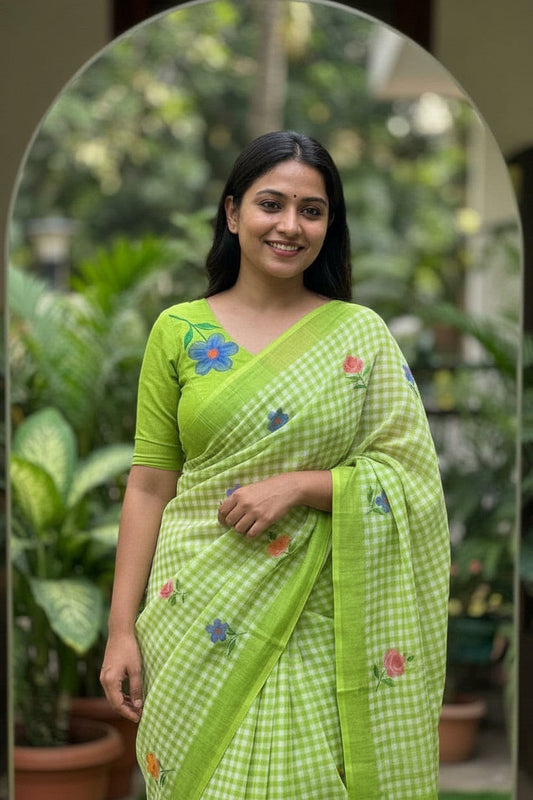 Woman in a green saree with floral patterns taking a mirror selfie.