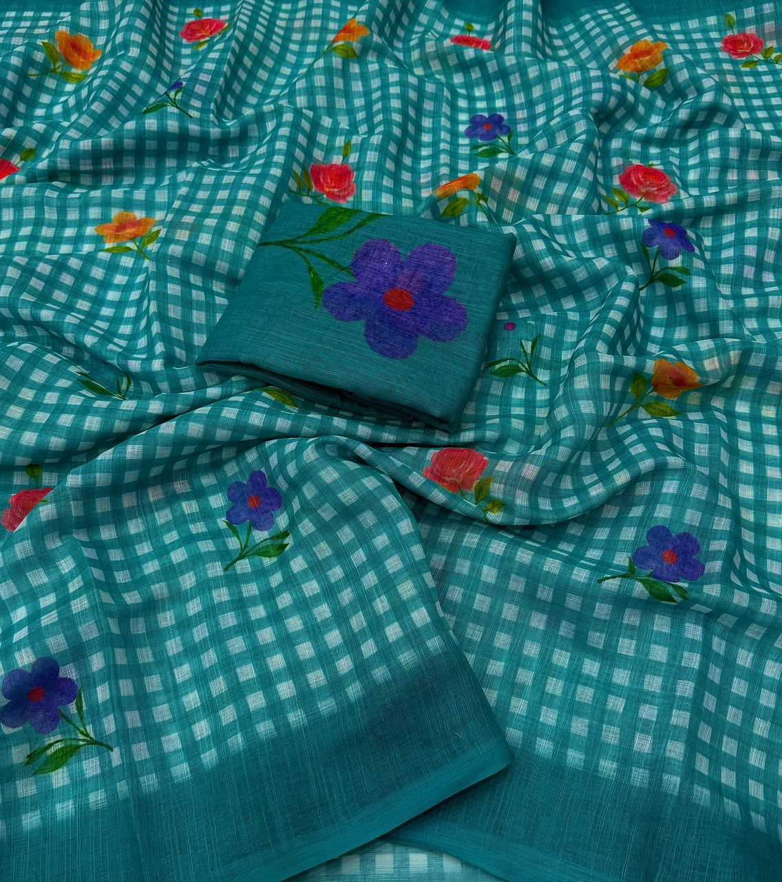 A teal and white gingham check saree with scattered embroidered floral motifs in purple, red, and orange, featuring a matching folded fabric piece with a large purple flower design.