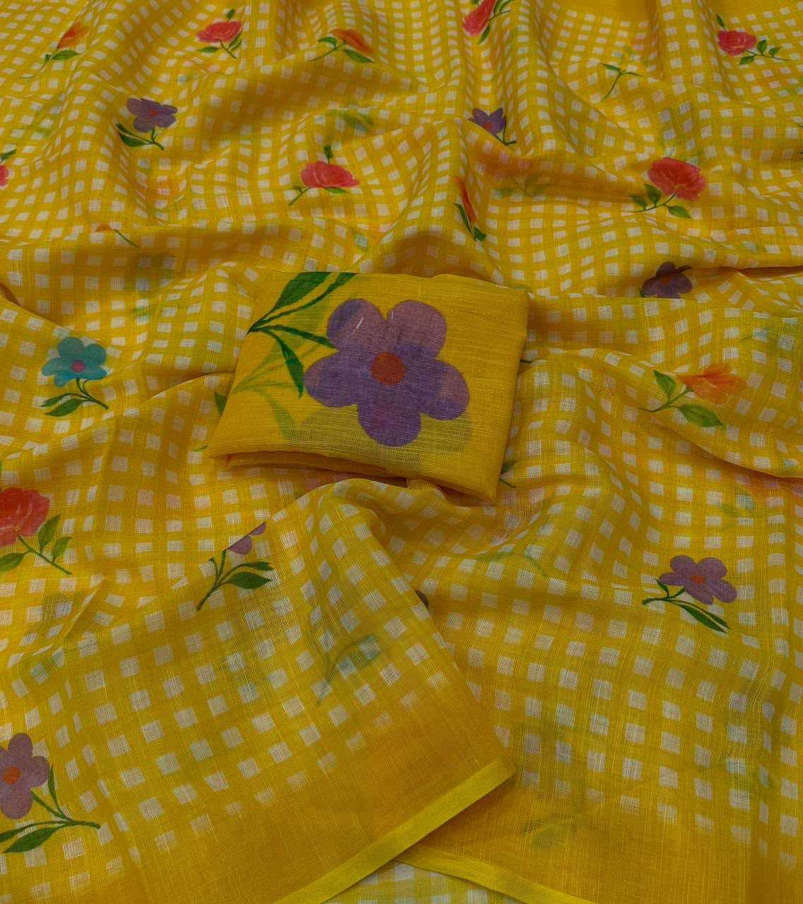 Yellow and white checkered saree fabric with scattered floral prints in purple, pink, and blue, featuring a matching yellow fabric piece with a large purple flower motif.